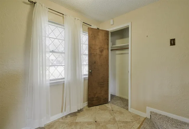 a view of an empty room with window and closet area