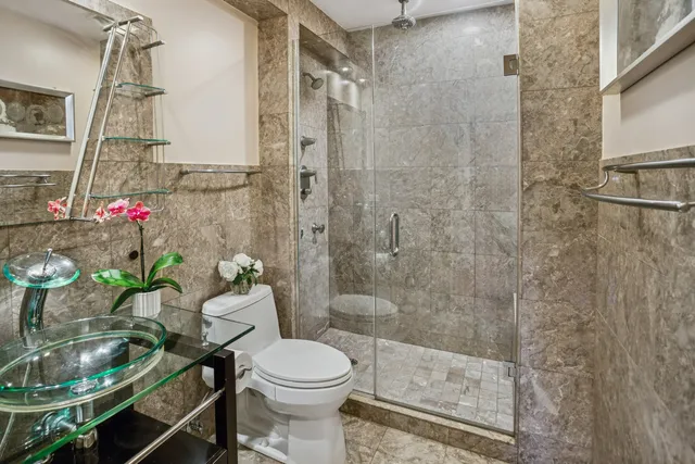 a view of a hallway with wooden floor and a bathroom