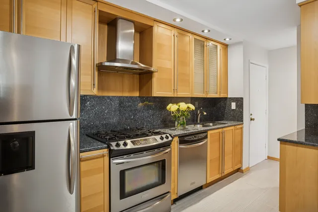 a kitchen with stainless steel appliances granite countertop a refrigerator a stove and a sink