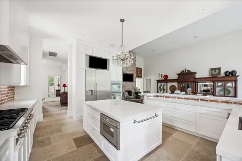 a kitchen that has a lot of white cabinets and stainless steel appliances