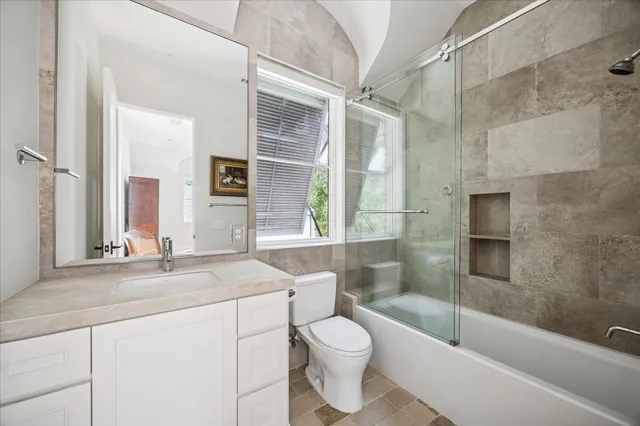 a bathroom with a granite countertop sink a toilet and shower