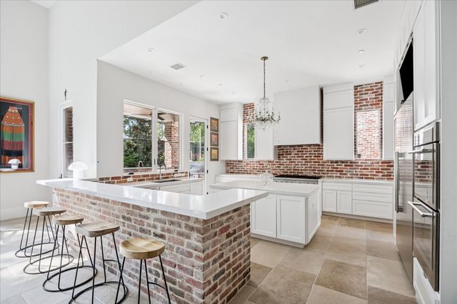 a large white kitchen with a stove a sink dishwasher and a refrigerator with wooden floor