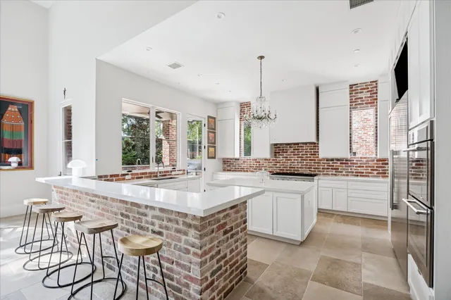 a large white kitchen with a stove a sink dishwasher and a refrigerator with wooden floor