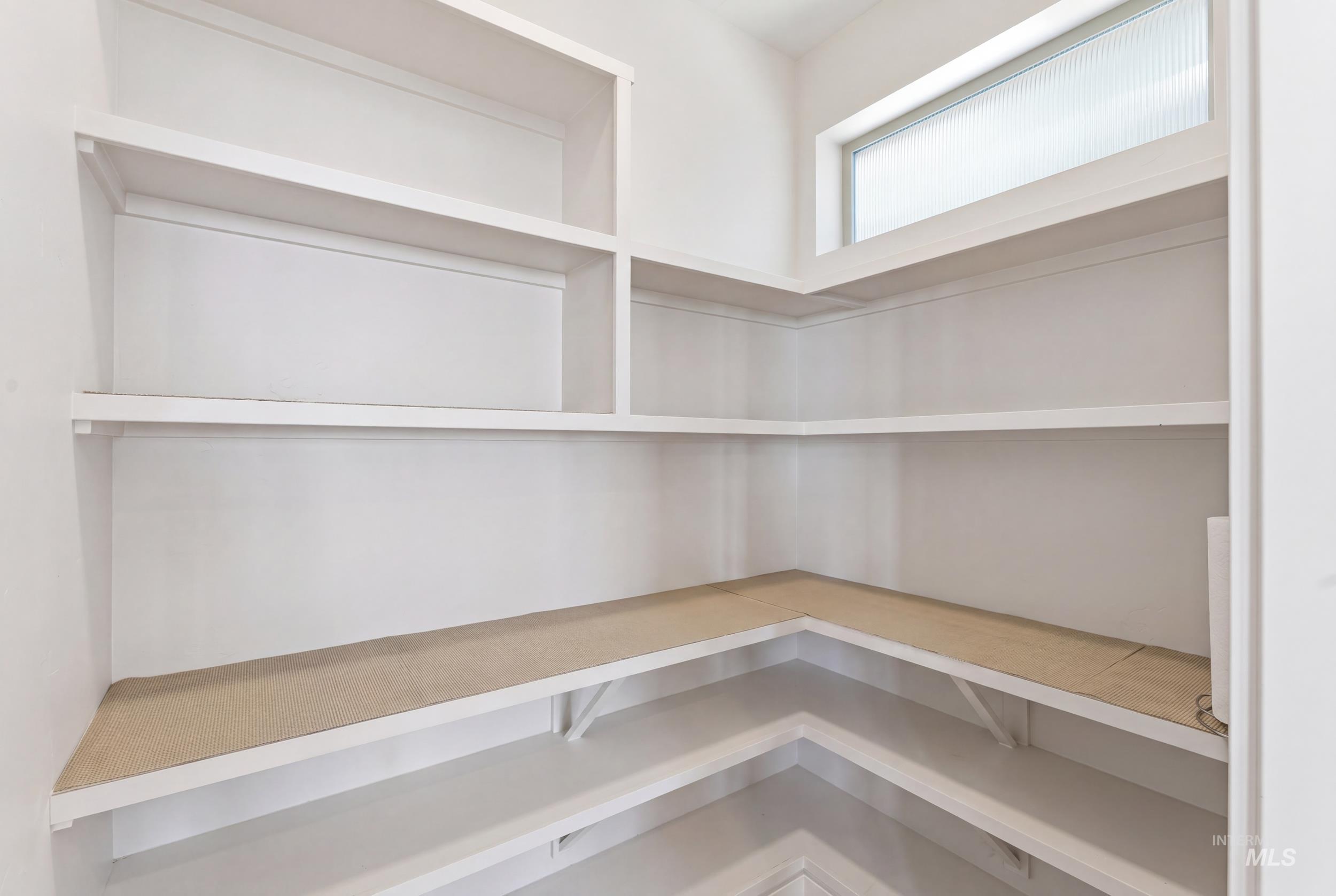 6347 South Utmost Lane Meridian, ID 83642 - Photo 12 of 37 Spacious walk-in pantry featuring built-in white shelving, corner shelving, and a horizontal transom window with frosted glass