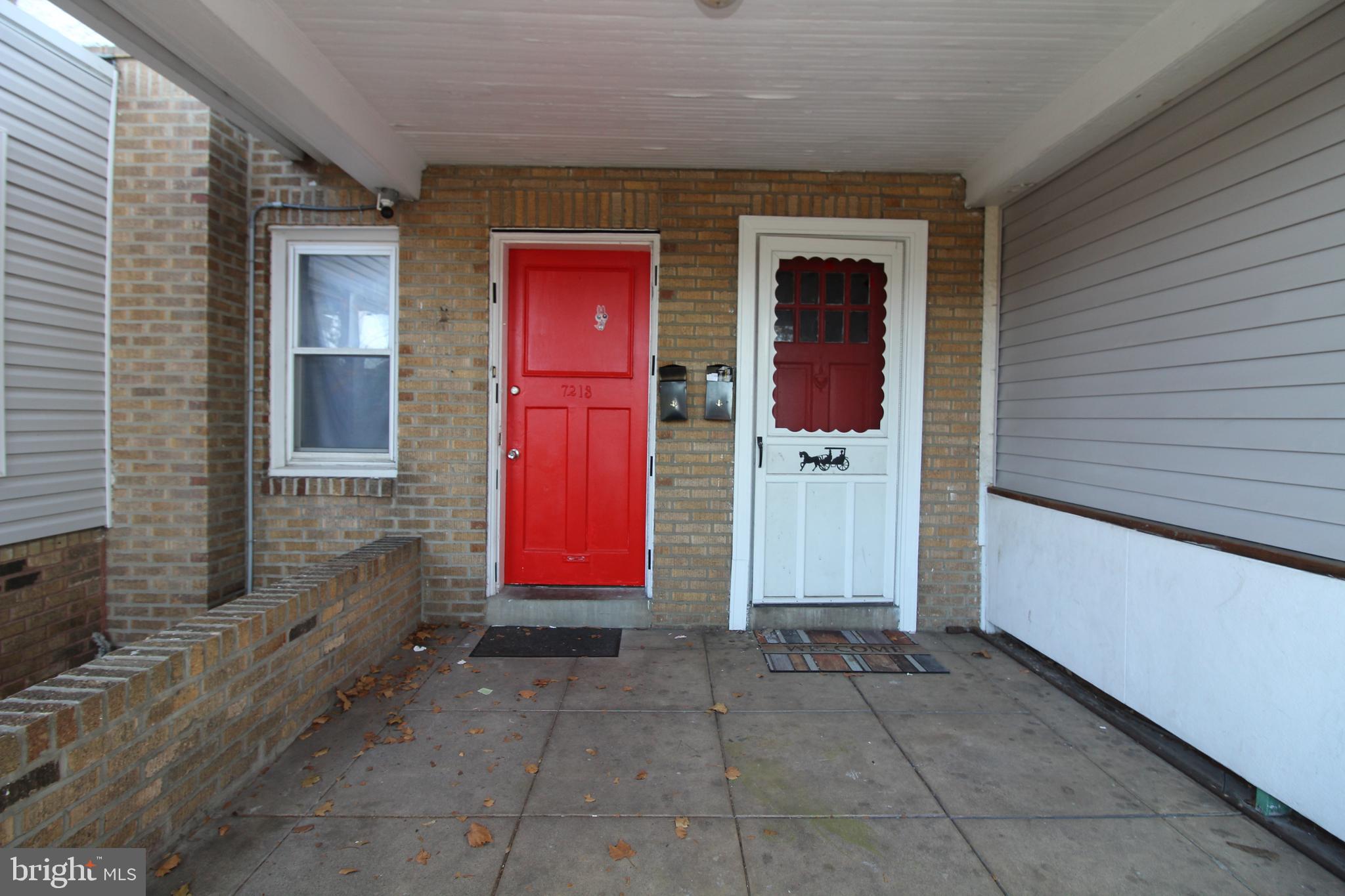 a view of a house with red door and brick walls