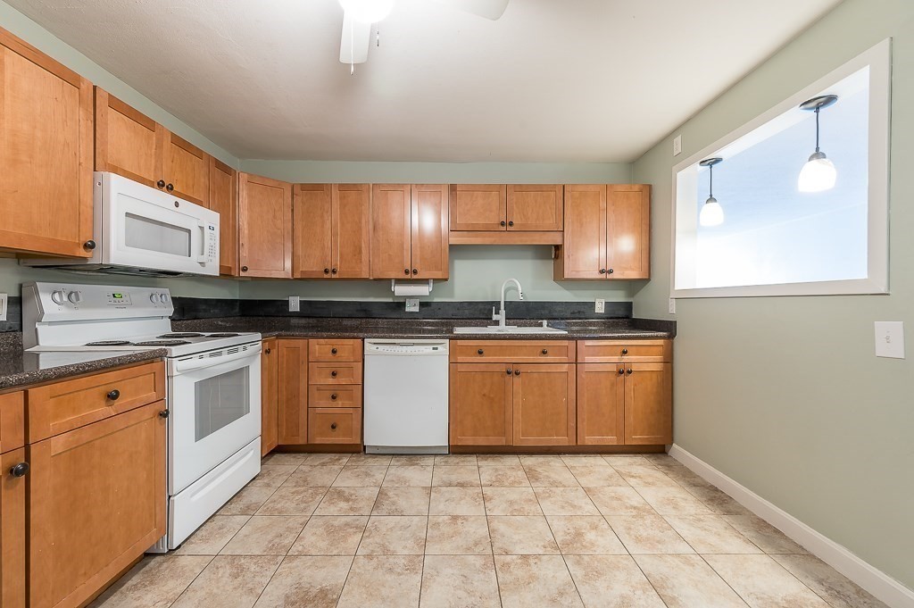 10 Wrentham Road, Unit 114 Worcester, MA 01602 - Photo 9 of 24 a kitchen with granite countertop a stove top oven sink and cabinets