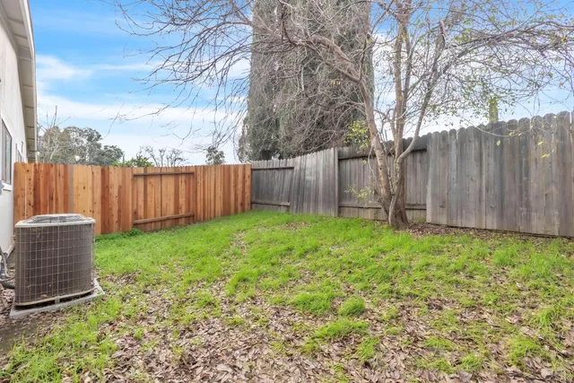 a backyard of a house with lawn chairs and wooden fence
