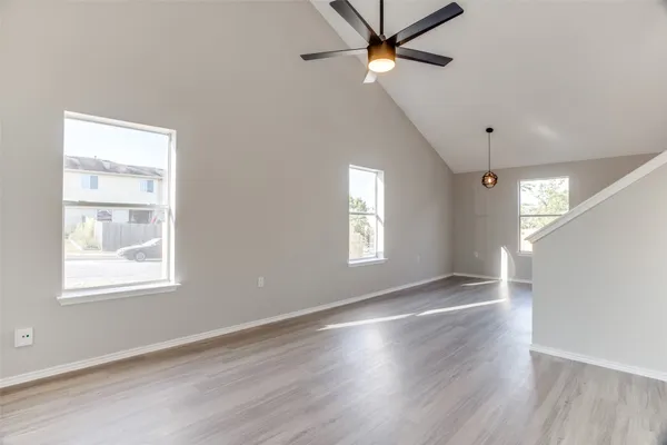 a view of an empty room with a window and wooden floor
