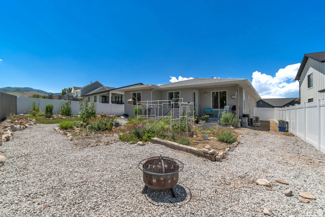 683 Kings Landing Tooele, UT 84074 - Photo 39 of 39 Expansive gravel backyard featuring a fire pit, established garden beds, and a white privacy fence