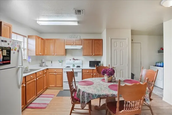 a kitchen with stainless steel appliances granite countertop a dining table chairs and a refrigerator