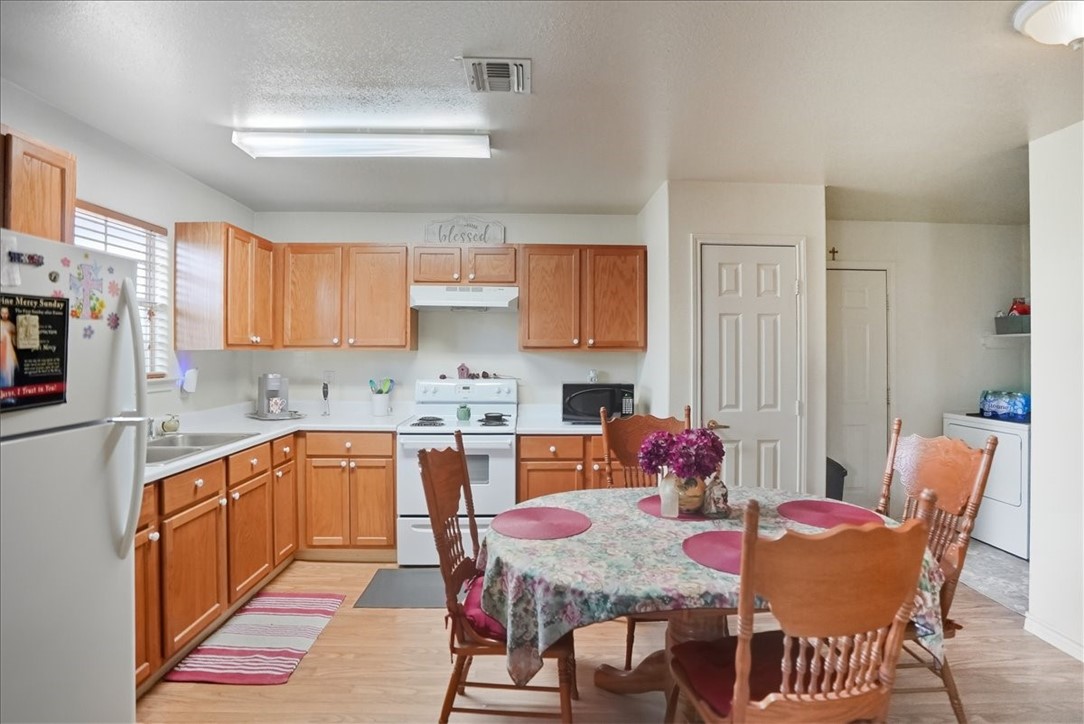 3260 Highway 281 George West, TX 78022 - Photo 5 of 34 a kitchen with stainless steel appliances granite countertop a dining table chairs and a refrigerator