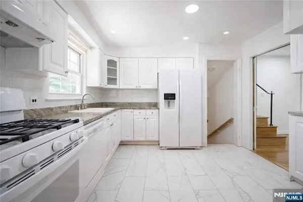 a kitchen with white cabinets and white appliances