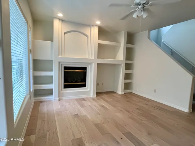 an empty room with wooden floor fireplace and windows