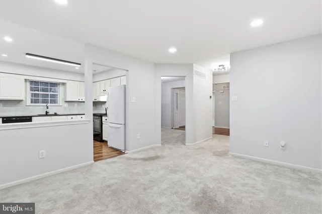 a view of a kitchen with refrigerator and white cabinets