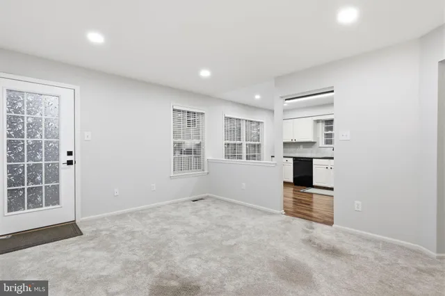 an empty room with kitchen view and windows