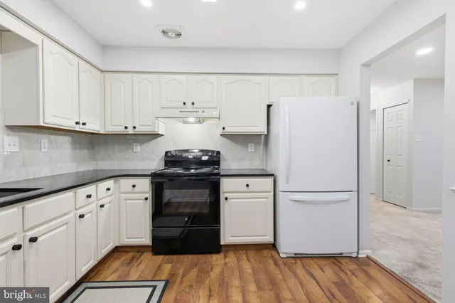 a kitchen with a refrigerator and white cabinets