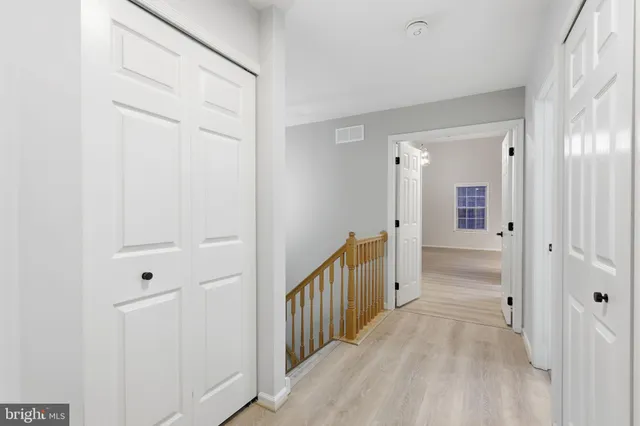 a view of a hallway with wooden floor and cabinet