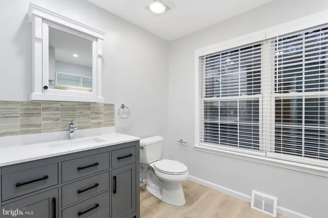 a bathroom with a toilet a sink a mirror and a window