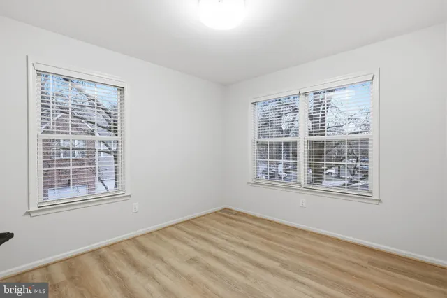 a view of an empty room with wooden floor and windows