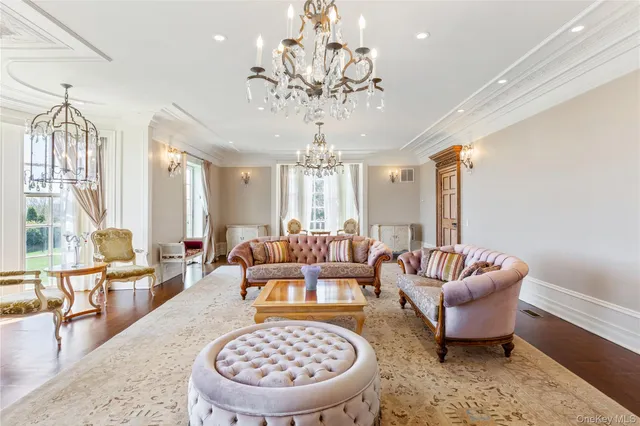 a living room with furniture a rug a chandelier and a large window