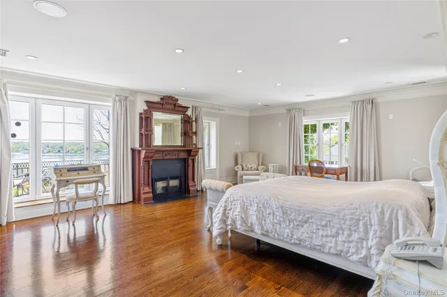 a bedroom with a large bed a fireplace and a large window with wooden floor