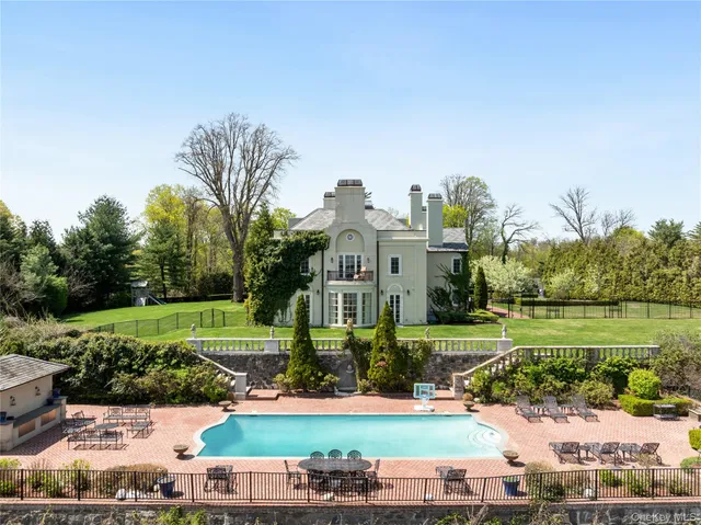 a view of a white house with a big yard and potted plants