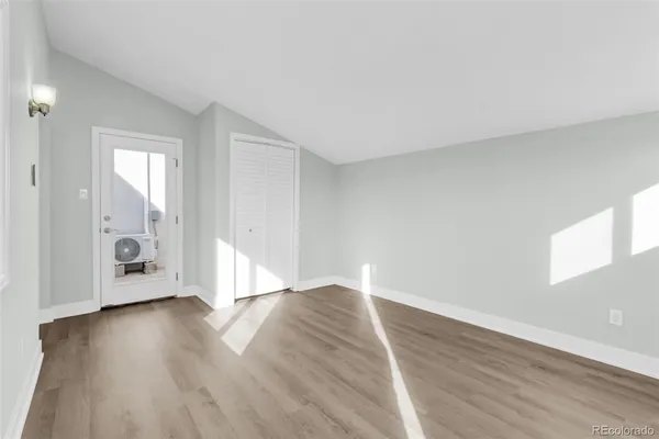 an empty room with wooden floor and windows