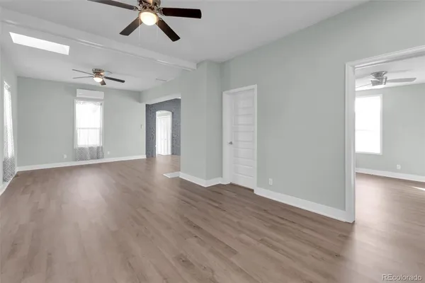 an empty room with wooden floor a ceiling fan and windows