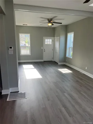 an empty room with wooden floor and windows