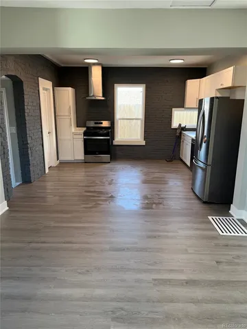 a view of a refrigerator in kitchen and an empty room