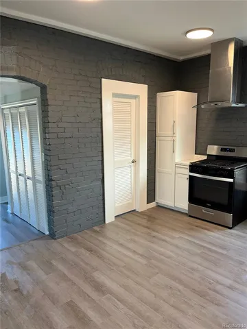 a view of empty room with wooden floor and kitchen