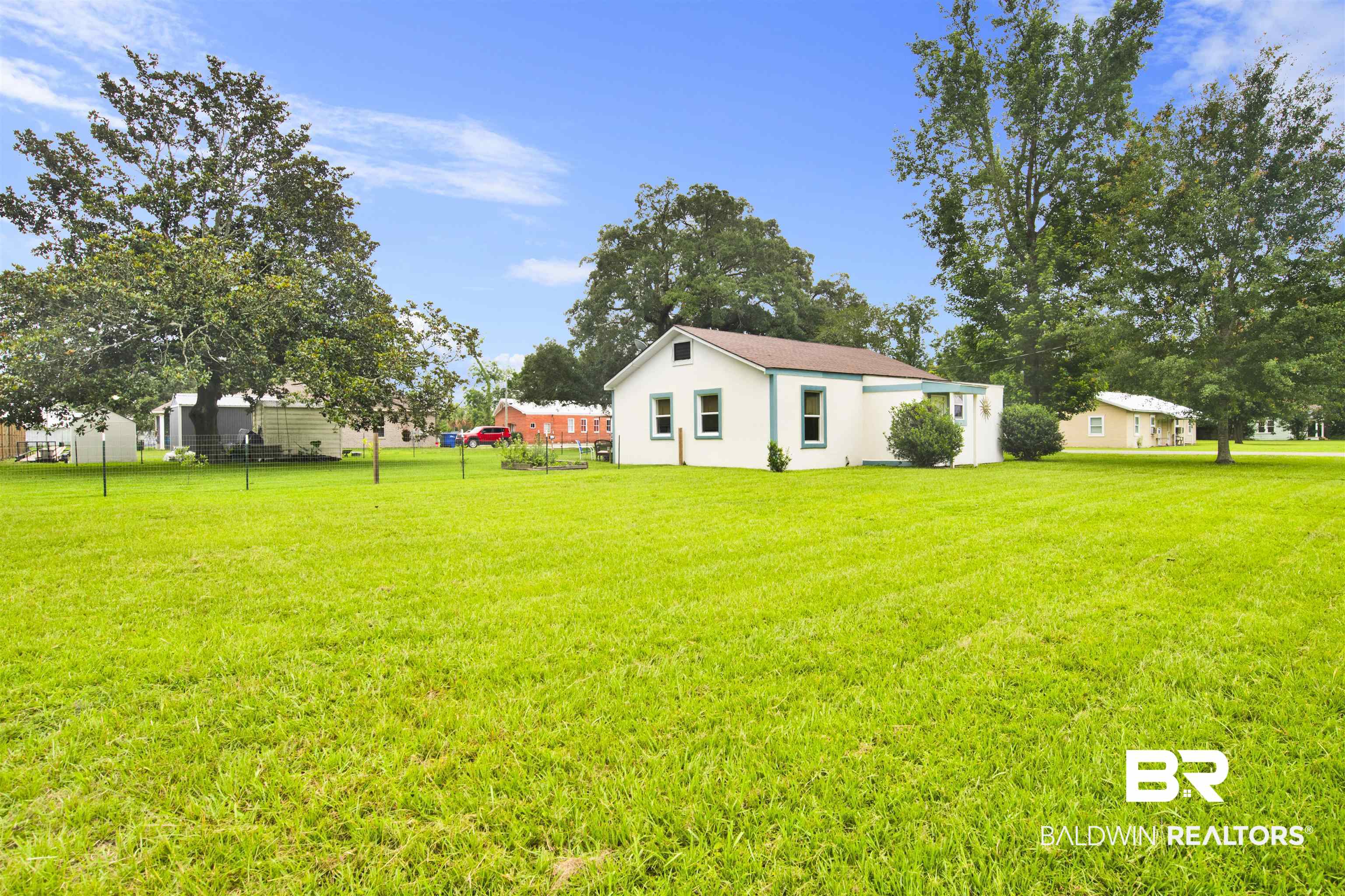 1100 North Pine Street Foley, AL 36535 - Photo 2 of 30 Expansive green lawn surrounding a white single-story residence with a brown roof and light green trim