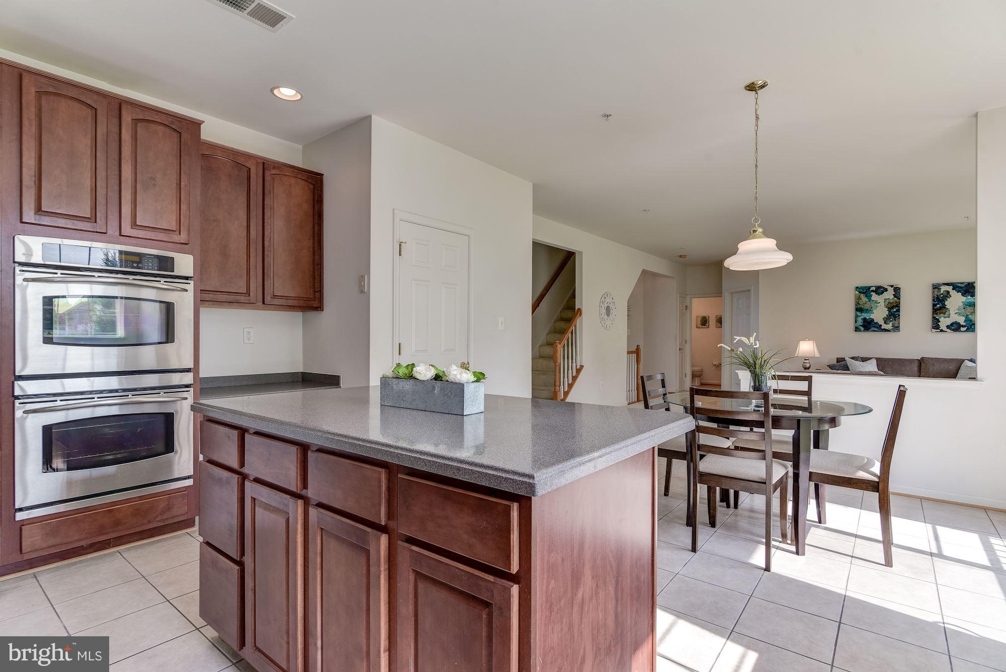 14629 Bubbling Spring Road Boyds, MD 20841 - Photo 8 of 30 a kitchen with stainless steel appliances granite countertop wooden cabinets a stove a oven a dining table and chairs