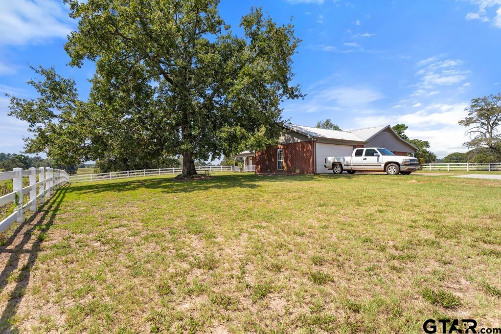 14762 County Road 3147 Tyler, TX 75706 - Photo 26 of 48 a swimming pool that has lawn chairs and a dining table under an umbrella