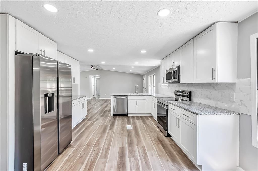 a large kitchen with a lot of counter space a sink and stainless steel appliances