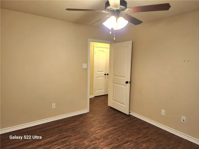 an empty room with wooden floor closet and windows