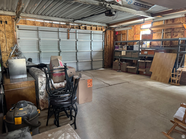 210 South State Street Moroni, UT 84646 - Photo 16 of 23 Attached garage with concrete flooring, overhead garage door, and exposed wood-paneled walls