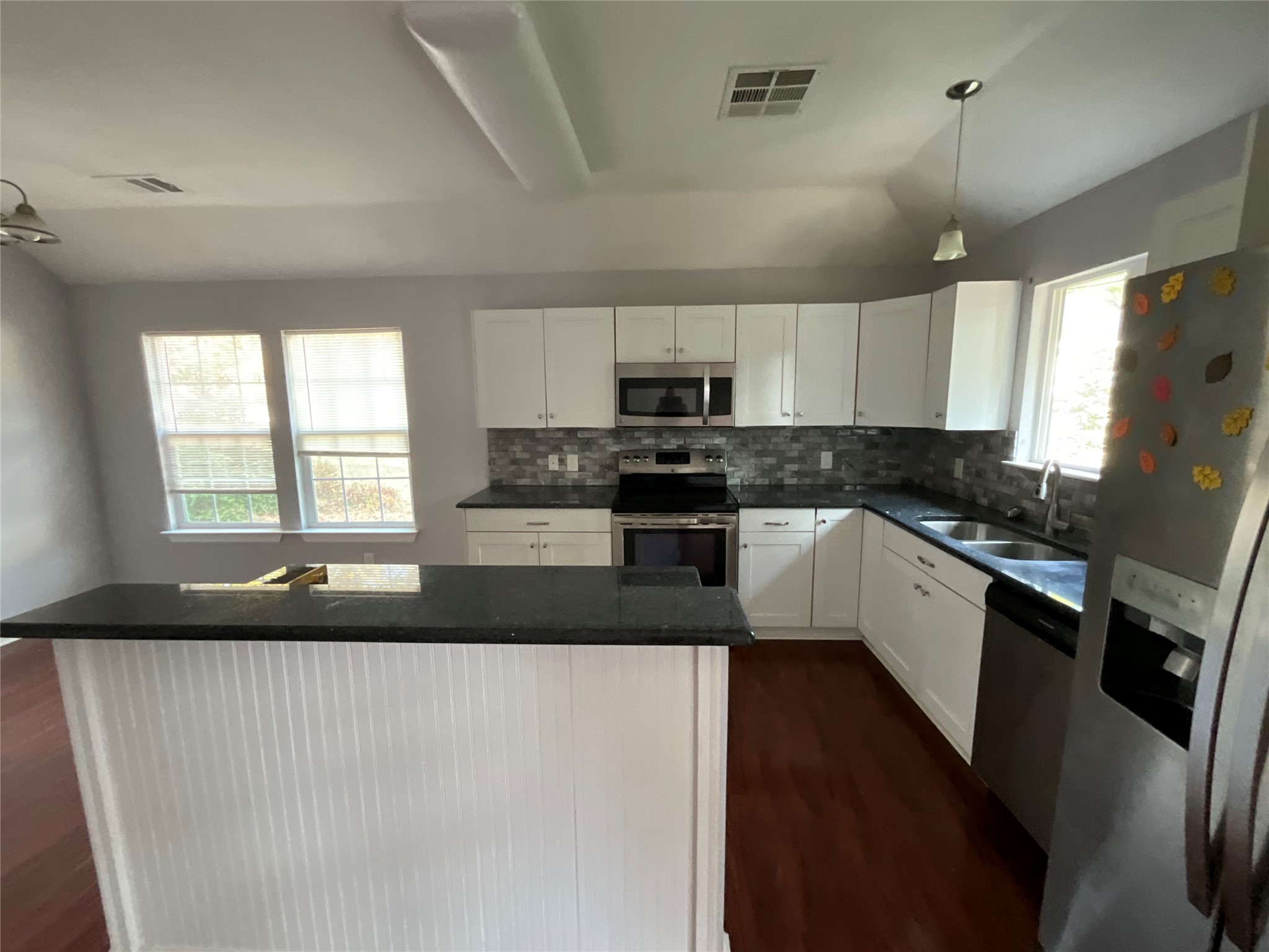 239 Old Firetower Road Bastrop, TX 78602 - Photo 22 of 39 Kitchen featuring appliances with stainless steel finishes, decorative light fixtures, a kitchen island, white cabinets, and decorative backsplash