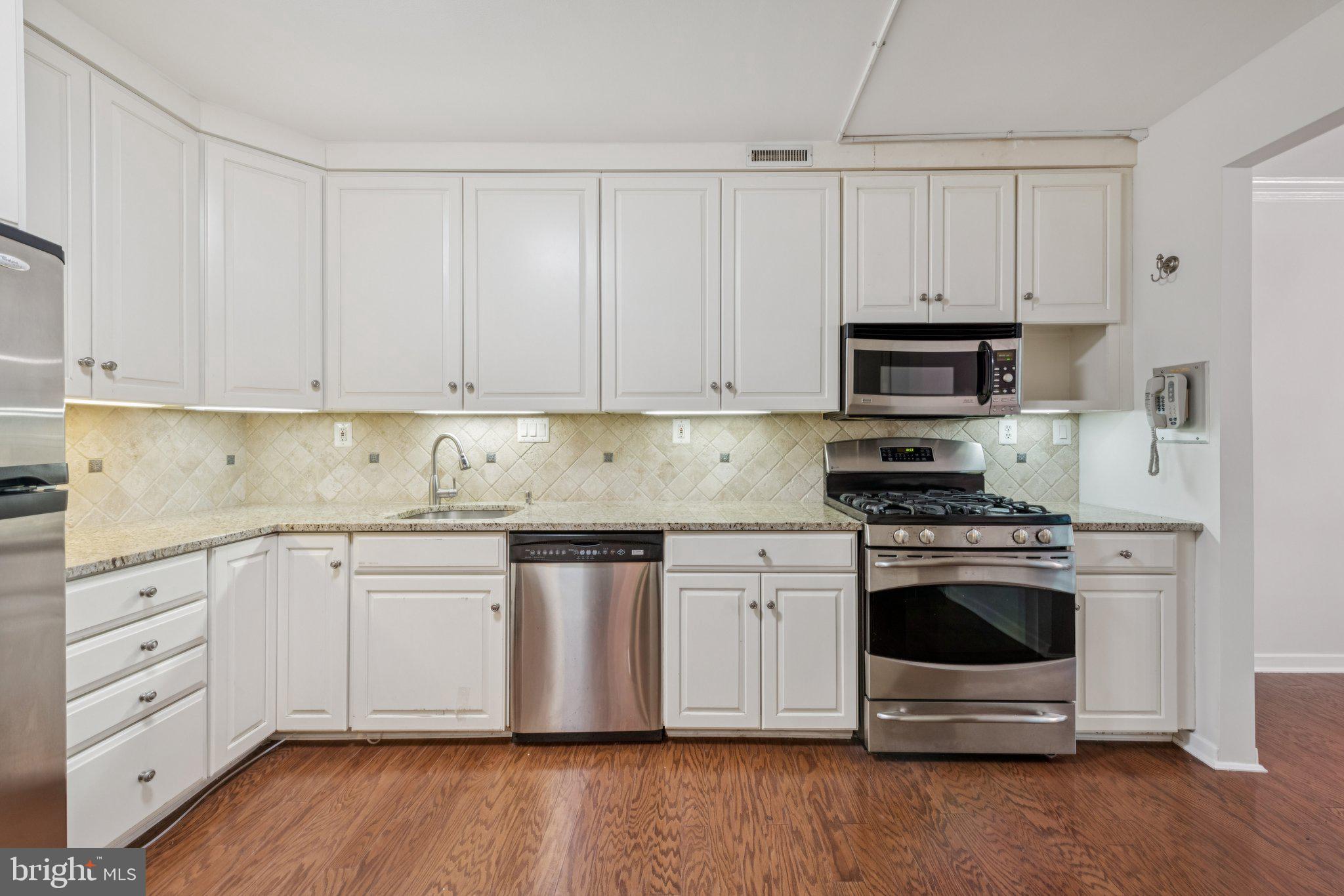 4100 Cathedral Avenue Northwest, Unit 406 Washington, DC 20016 - Photo 2 of 30 a kitchen with white cabinets and stainless steel appliances