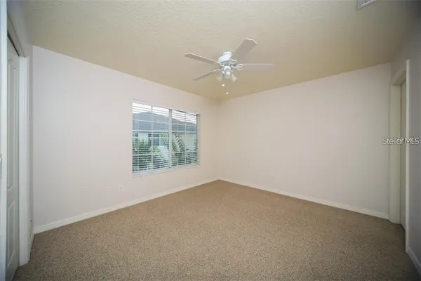 an empty room with a window and a fan