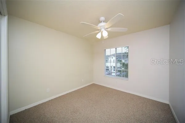 an empty room with windows and fan