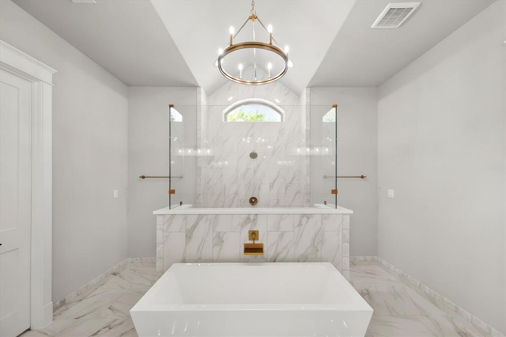 7631 Woodstream Road Midlothian, TX 76065 - Photo 25 of 40 Freestanding soaking tub, large format marble-look tile flooring, marble-look tile shower surround, arched window, and a chandelier lighting fixture