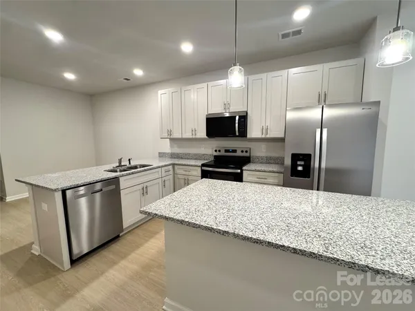 a kitchen with stainless steel appliances granite countertop a sink refrigerator and microwave