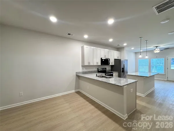 a large white kitchen with kitchen island a sink dishwasher a stove and a refrigerator with wooden floor