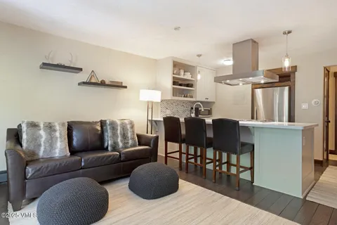 a living room with furniture kitchen view and a wooden floor