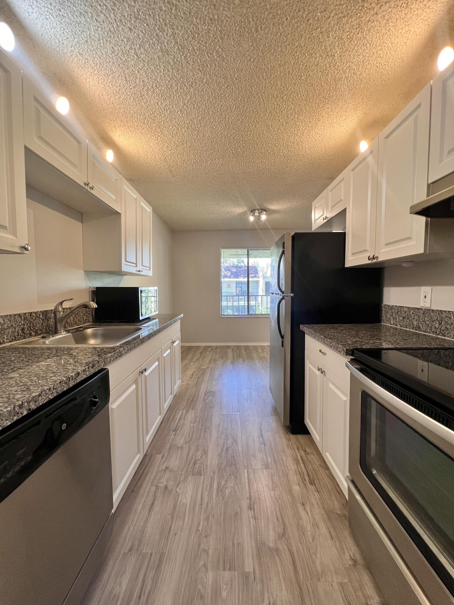 150 Pineview Road, Unit J5 Jupiter, FL 33469 - Photo 2 of 35 a large kitchen with stainless steel appliances granite countertop a stove a sink and a microwave