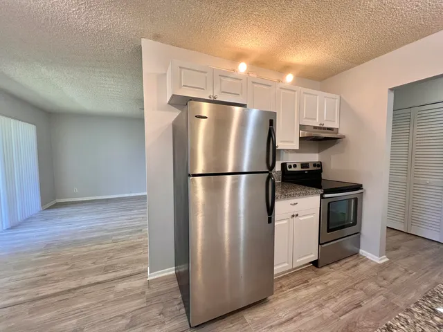 a kitchen with cabinets stainless steel appliances and wooden floor