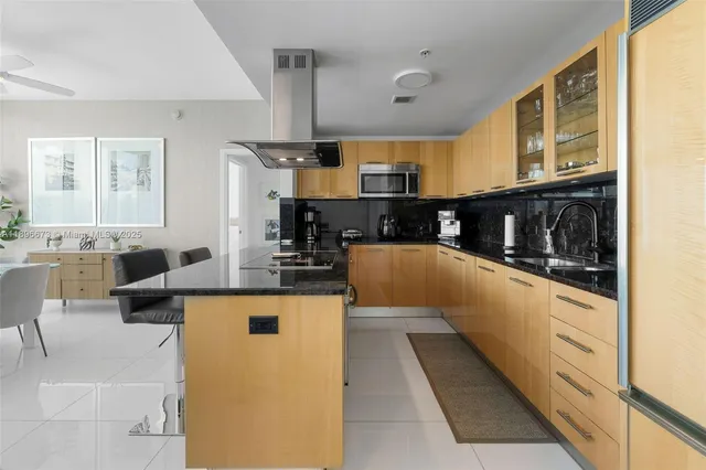 a large kitchen with stainless steel appliances a large counter top a stove a chimney a sink and a large window