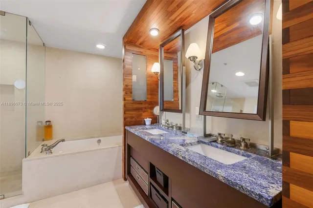 a bathroom with a tub a sink and mirrors