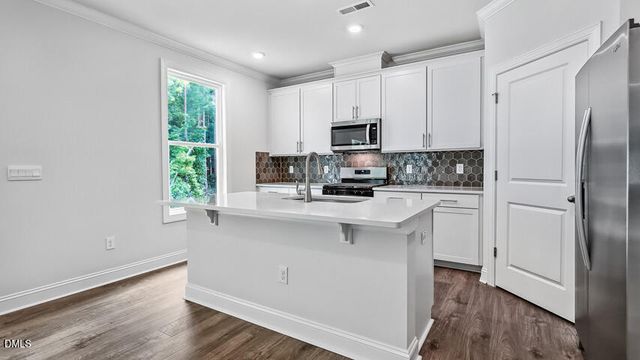 a kitchen with white cabinets and wooden floor